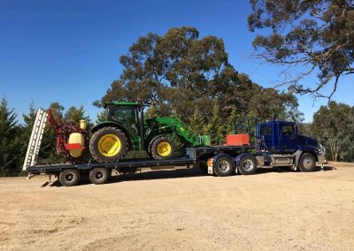 A semitrailer loaded with a large weed spraying machine and a large front end loader Adelaide Hills